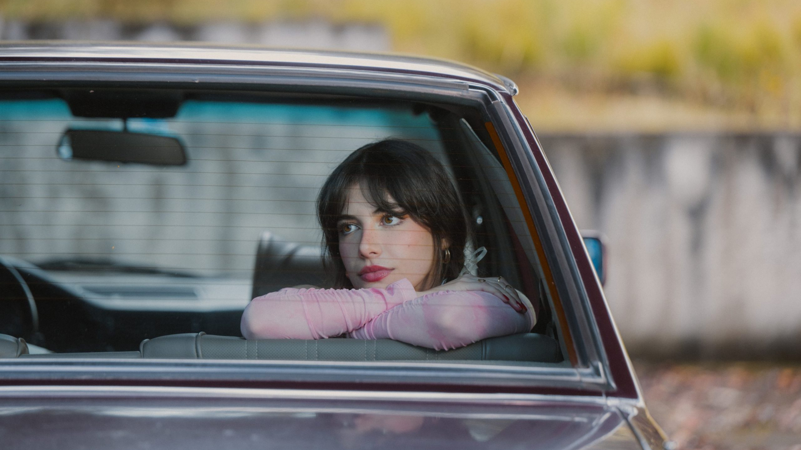 Milo posa dentro de un automóvil durante una sesión fotográfica promocional de su proyecto musical.