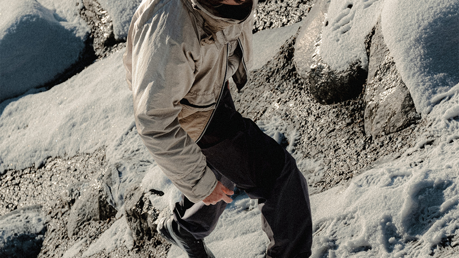 Explorador caminando sobre terreno rocoso en un paisaje natural, como parte de la narrativa Salomon ADVANCED SS26.