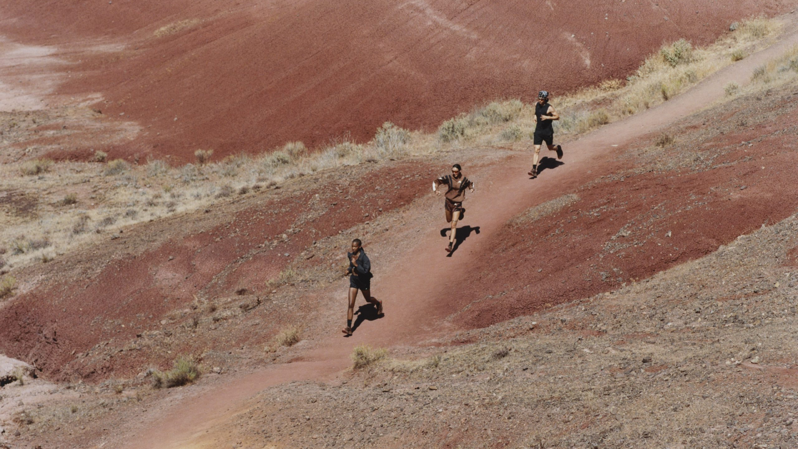 Corredores en paisaje desértico rojo usando adidas Humanrace Adizero EVO SL Mars durante sesión de running.
