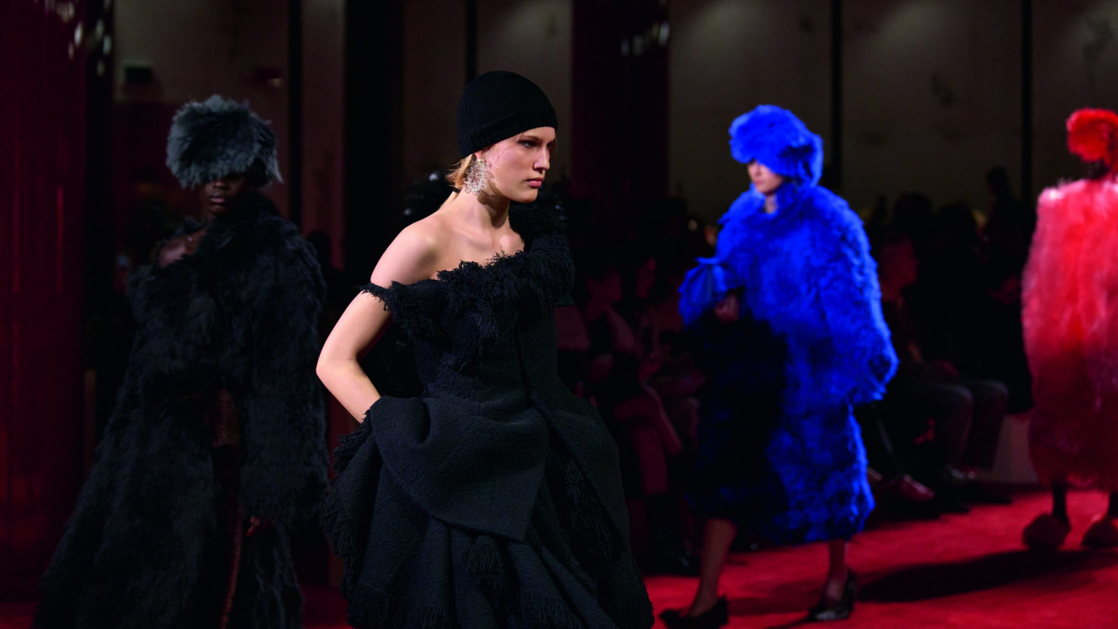 Modelo en pasarela de Bottega Veneta Winter 2026 en Milán con vestido negro estructural y texturas que evocan piel, durante el desfile en Milan Fashion Week.