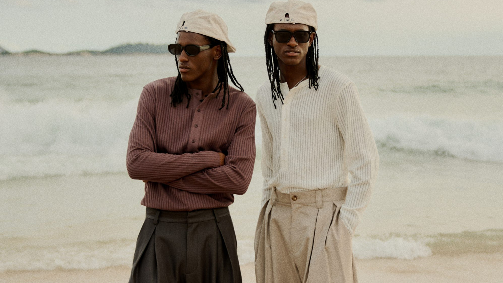 Modelos con looks relajados de BERSHKA menswear en la playa con pantalones amplios y knit ligero.