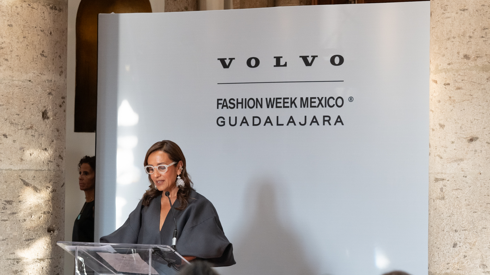 Mujer dando discurso en conferencia de prensa de Volvo Fashion Week México Guadalajara frente a un podio.
