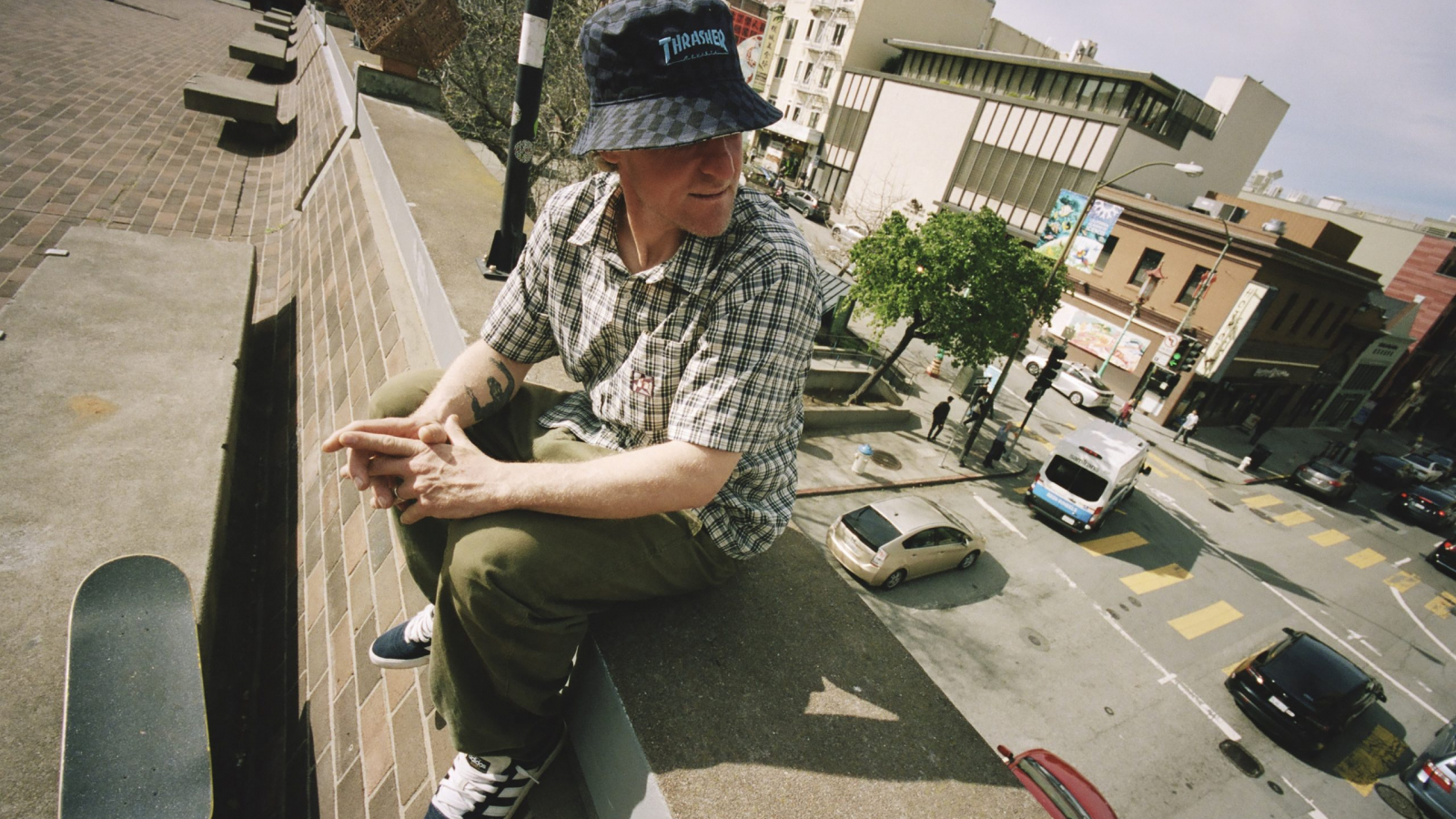 Skater sentado en una estructura urbana usando prendas de la colección adidas Skateboarding x AFA junto a Thrasher, en una escena inspirada en la cultura callejera y el espíritu del skate en San Francisco.