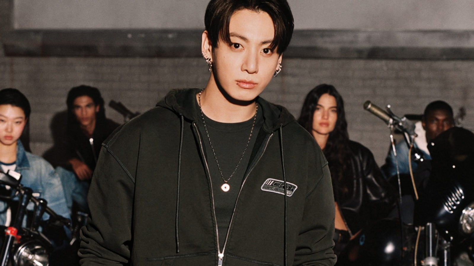 Jung Kook posa frente a motocicletas usando prendas de la colección cápsula Jung Kook for Calvin Klein, inspirada en la estética biker y el estilo urbano contemporáneo.