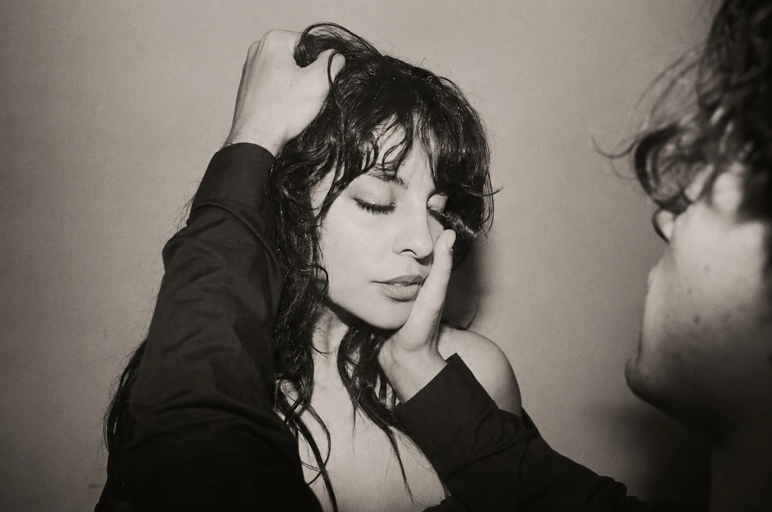 Girl Ultra con los ojos cerrados y una mano sobre el cabello en una fotografía en blanco y negro.