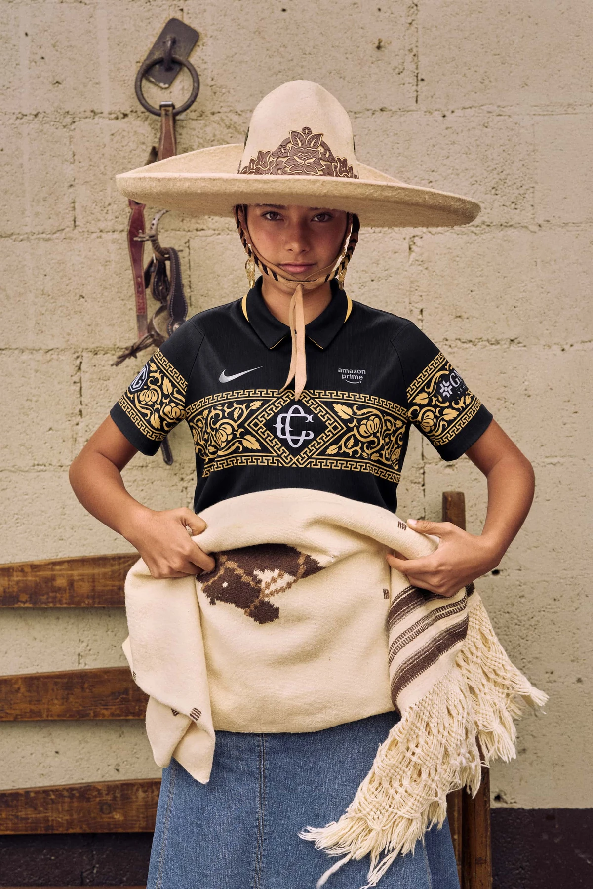 Participante de la campaña Herencia Sagrada con sombrero de charro y el jersey negro y dorado de Chivas.