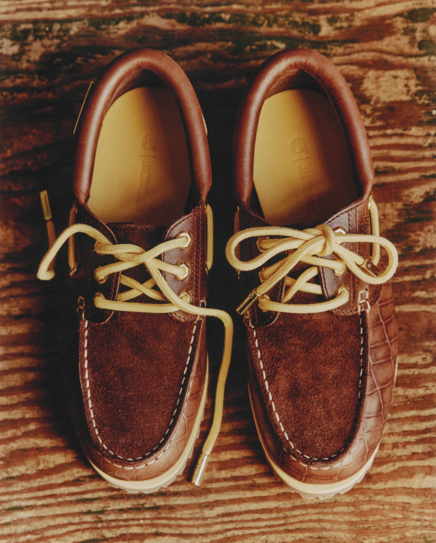 Par de náuticos Timberland x Jacquemus en café oscuro con agujetas claras, vistos desde arriba sobre una alfombra.